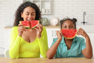 Sticker - Beautiful young African-American woman and her cute daughter with pieces of fresh watermelon at table in kitchen