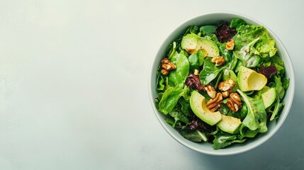 A fresh salad bowl with mixed greens, avocado, and nuts on a clean background, with space for copy or branding.