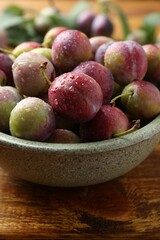 Wall Mural - Ripe plums in bowl on wooden table, closeup