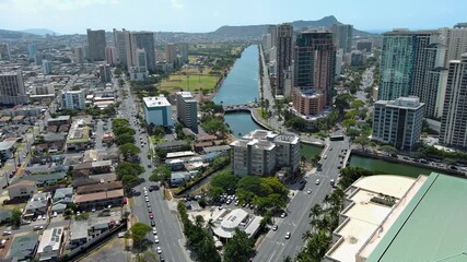 Wall Mural - tilt aerial footage of skyscrapers, hotels and condos, Ala Wai Canal, lush green trees, the Punch Bowl and cars driving on the street in Honolulu Hawaii USA