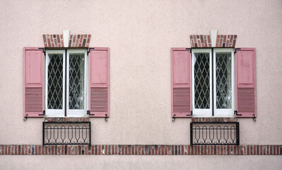 Canvas Print - Stucco house wall with windows with pink shutters