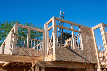 Wall Mural - Summer construction season, new house build at the framing stage, aluminum extension ladder on 2nd floor leaning against exterior wall, early morning sunny day
