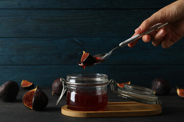 Sticker - Glass jar with fig jam and spoon in hand, cut figs on wooden background