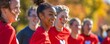 © Boontharika - Cheerful group of young people in red shirts outdoors, enjoying a sunny day with vibrant fall foliage in the background.