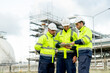 © narong - Factory engineer or technician workers with one hold tablet and the other look at tablet and they also stand in front of refining and petrochemical factory and tank with day light.