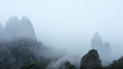 Canvas Print - Dense fog is engulfing the rocky peaks of a mountain range, creating a mysterious and spooky atmosphere reminiscent of halloween