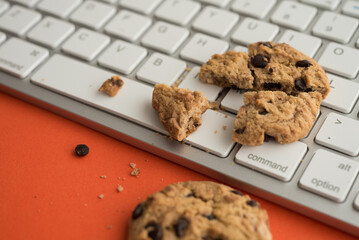 Broken chocolate chip cookies on keyboard computer background. Cookies website internet homepage policy accpeted or blocks, technology internet website concept.