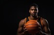 © Introvertia - Focused basketball player holding ball in front of him against black background