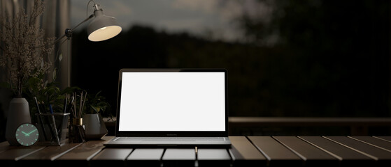 Poster - A laptop on a desk in a dark room at night, illuminated by a table lamp.