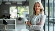 © JINGWEN - Confident businesswoman with crossed arms smiling in modern office, facing camera, embodying success in professional attire with sleek hairstyle.