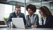 © halo - A portrait of three diverse business professionals smiling while working on a laptop in an office.