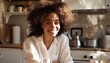 © DruZhi Art - Smiling Woman Sitting in Kitchen with Coffee Wearing White Shirt Curly Hair White Cabinets Relaxed Scene