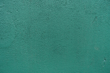 Grainy surface of dark teal green painted wall