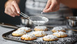 © Oleksiy - Woman with sieve sprinkling powdered sugar onto cookies at grey textured table, closeup