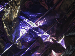 Wall Mural - purple light reflects on silver plastic sheet for abstract dark background.