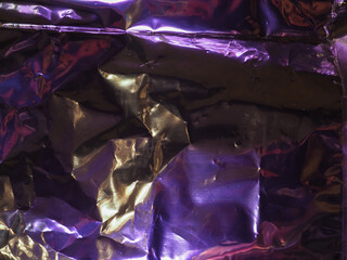 Wall Mural - purple light reflects on silver plastic sheet for abstract dark background.