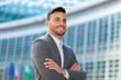 © Minerva Studio - Smiling young businessman in a suit standing confidently outside