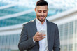 © Minerva Studio - Smiling businessman using smartphone outdoors
