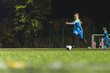 © PoppyPix - cute little girl with blue uniform kicking a ball at the evening match, full shot. High quality photo