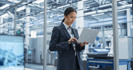 Poster - Asian Factory Manager Working on Laptop at Futuristic Industrial Manufacture with Autonomous Robotic Assembly Line. Specialist Monitoring Production, Planning Work for Employees