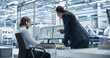 © Gorodenkoff - Handsome Engineer and a Beautiful International Business Manager Having a Conversation and Using Desktop Computer. Specialists Setting Up Production Values at an Electronics Assembly Plant