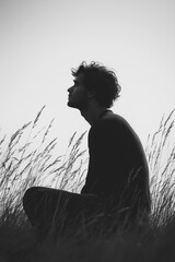 Poster - A man is sitting in a field of tall grass. He is looking off into the distance, and the scene is quiet and peaceful
