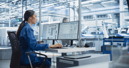 Fototapete - Experienced Female Software Developer Working in Office, Using Desktop Computer and Overlooking Production at a Modern Automated Electronics Manufacture with Robotic Arms. Administrator at Work