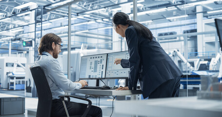 Fototapete - Handsome Engineer and a Beautiful International Business Manager Having a Conversation and Using Desktop Computer. Specialists Setting Up Production Values at an Electronics Assembly Plant