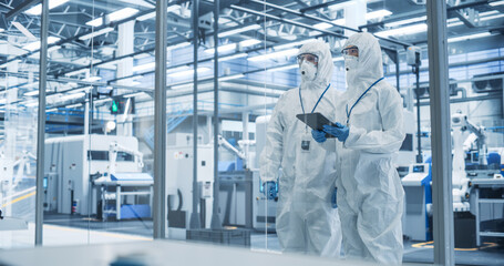 Fototapete - Development Factory Cleanroom: Engineers Wearing Coveralls and Goggles while Talking and Using a Tablet Computer. Scientists Working in Advanced Electronics Manufacture with Precision Machinery