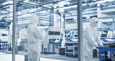 Leinwandbilder - Industrial Scientist Wearing Disposable Protective Suit to Be Protected From Chemical and Biological Dangers. Female Using Tablet, Monitoring Production Process at a Biotechnology Plant