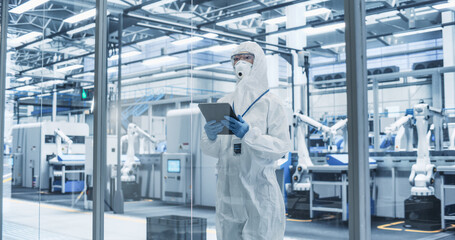 Fototapete - Portrait of Female Worker Wearing Full-Body Protective Coveralls, Mask and Goggles at a Biotechnology Manufacturing Plant. Young Specialist Using a Tablet Computer, Overlooking Nanotech Production