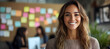 © Earny - A cheerful woman smiling in a modern office setup, exuding positivity and confidence in a collaborative workspace.