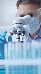 Man scientist with protective glasses, mask and gloves is using microscope in laboratory, vertical portrait of researcher. Microbiology and science