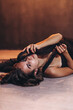 © Karina Оsokina - brunette woman in a black dress lies on the floor in a photo studio