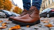 © lililia - An adult man walks down a cobblestone path, wearing blue jeans and brown leather boots, surrounded by parked cars and autumn foliage