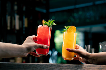 Close up of two people cheering cocktails in bar or disco club drinks and cocktails concept