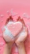 © COK House - Child holds pink heart-shaped item in soapy hands on pink backdrop.