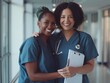© kinara art design - Two healthcare professionals smiling together in a hospital corridor.