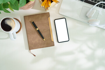 Wall Mural - Top view smart phone with empty screen, notebook and coffee cup on wooden office desk. Copy space for your text.