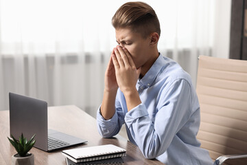 Wall Mural - Young man suffering from sinusitis at wooden table indoors