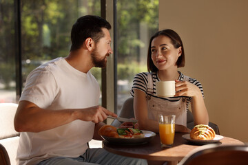 Poster - Happy couple having tasty breakfast in cafe