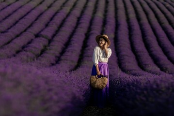 Canvas Print - A woman stands in a field of lavender flowers, wearing a straw hat