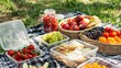 © buraratn - A picnic blanket with food containers holding fresh fruits, cheese, and crackers
