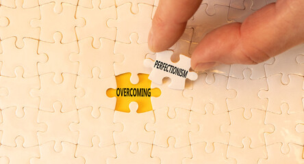 Overcoming perfectionism symbol. Concept words Overcoming perfectionism on beautiful white puzzles. Beautiful yellow background. Businessman hand. Business Overcoming perfectionism concept. Copy space