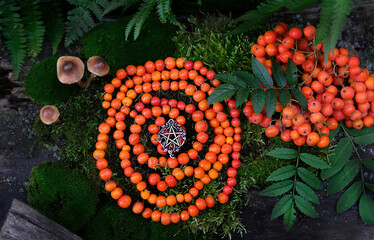 protective rowanberry spiral with pentacle amulet in forest, natural background. Magic ritual, Witchcraft. Wiccan esoteric practice with handmade beads of rowan berry for protect, positive spirit