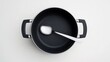 © MakoPoko - Spoon resting in a modern cooking pot, isolated on a white background, representing simplicity in kitchenware design and a minimalist culinary setting.