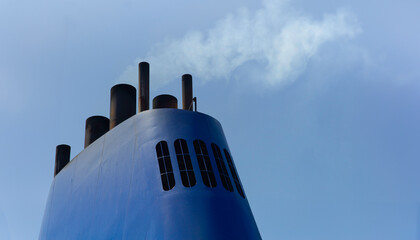 Wall Mural - Blue chimney with dirty polluting plume of smoke on a ferry or cruise ship at blue sky