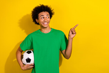 Sticker - Photo of attractive funny guy wear green t-shirt playing football showing emtpy space isolated yellow color background