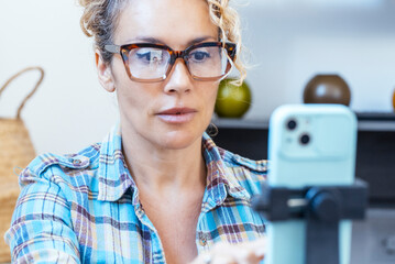 Modern adult woman preparing her smartphone for recording a video or making a video call, highlighting the use of technology for online work or leisure activities. Perfect for influencers or content c