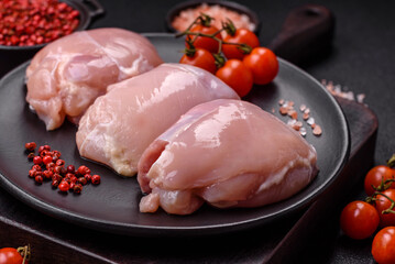 Fresh chicken fillet on a dark concrete table with spices and herbs